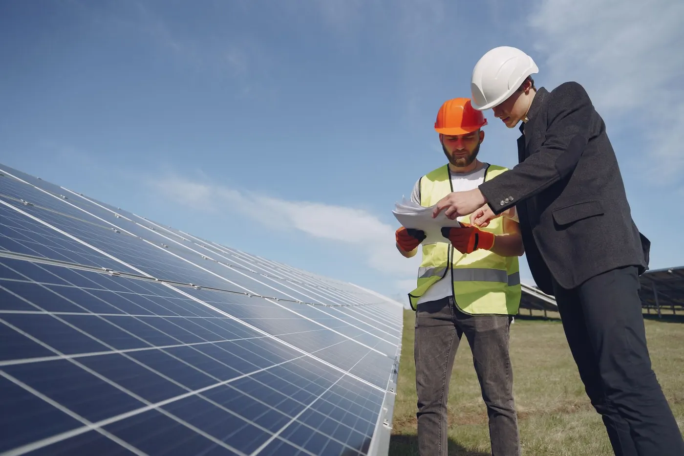 Inspector and foreman checking documentation beside solar panels
