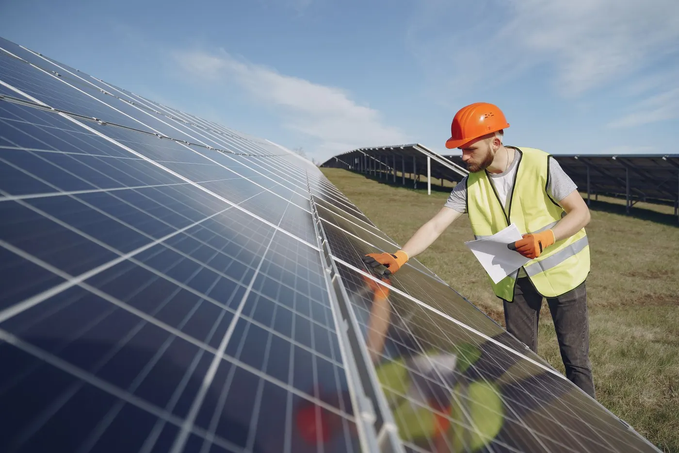 Service engineer with a hard hat checking a solar panel string